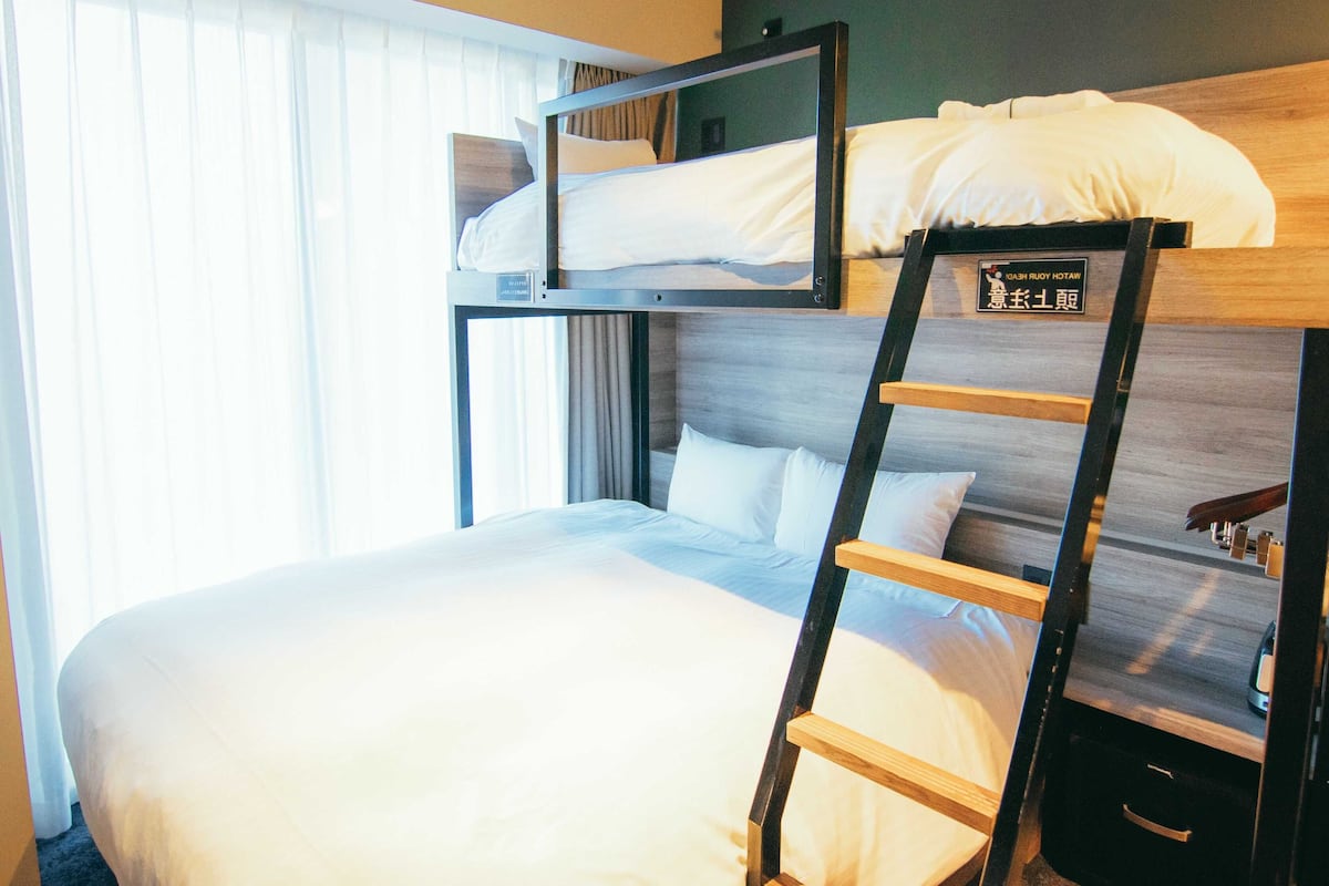 A bunk bed with a ladder, white bedding, and a wooden headboard.