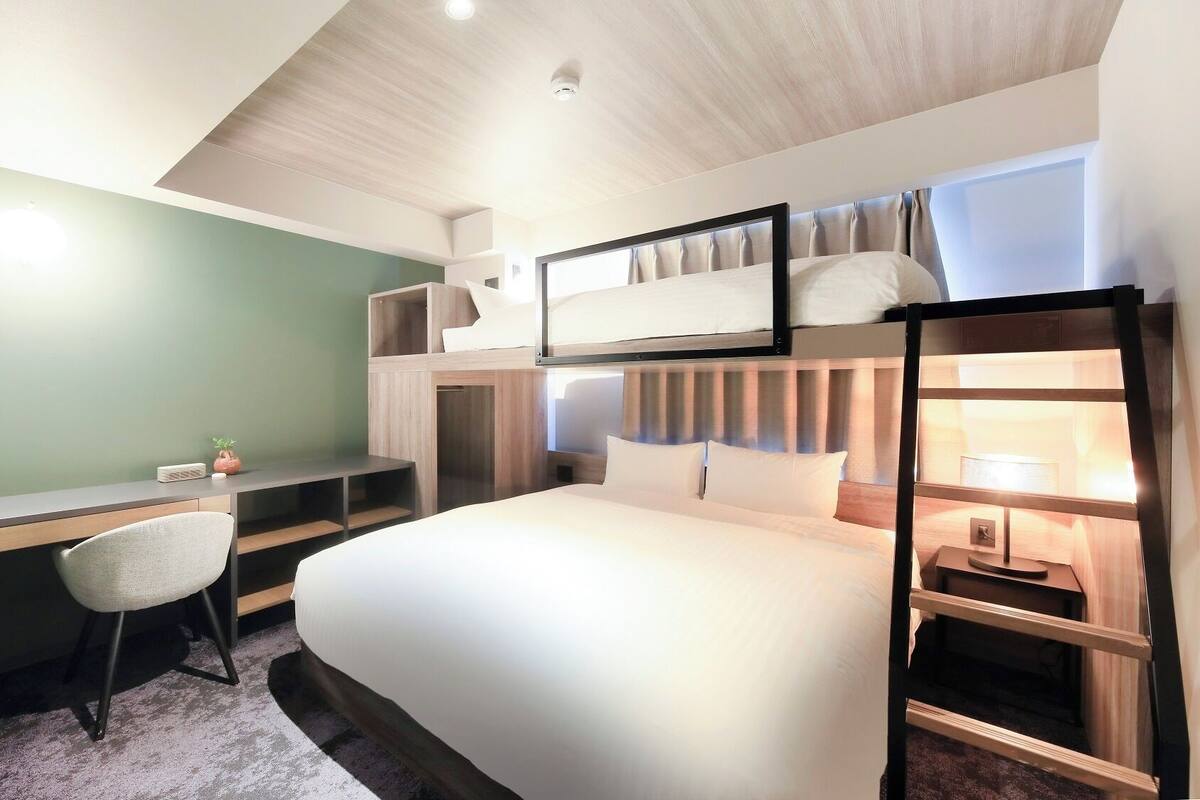 A bunk bed room with a desk, chair, and a small plant.