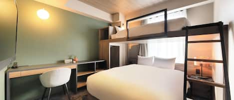 A hotel room with a bunk bed, a desk with a chair, a bedside table with a lamp, and a window with curtains.