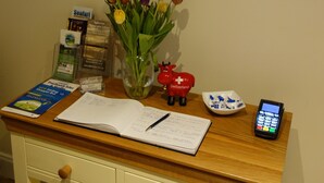 A desk with a vase of tulips, a red piggy bank, a mobile phone, and some documents.