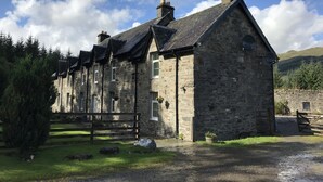 A stone building with a traditional architectural style, featuring multiple chimneys and a pitched roof.