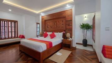 A modern hotel room with a large bed, wooden headboard, and a potted plant.