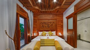 Un dormitorio espacioso con techo de madera, una cama grande con almohadillas amarillas y vistas al exterior a través de una puerta corrediza.