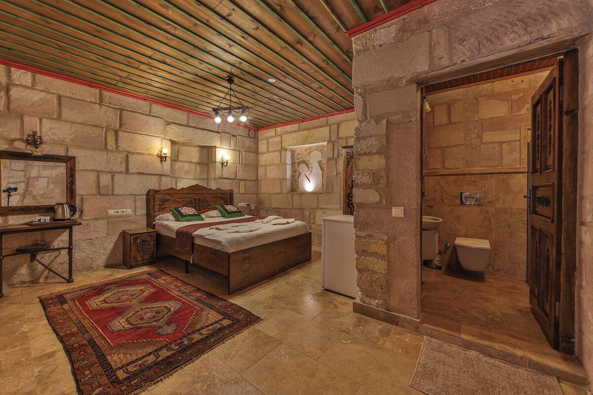 A bedroom with a wooden bed, a nightstand, a dresser, a mirror, and a red patterned rug.