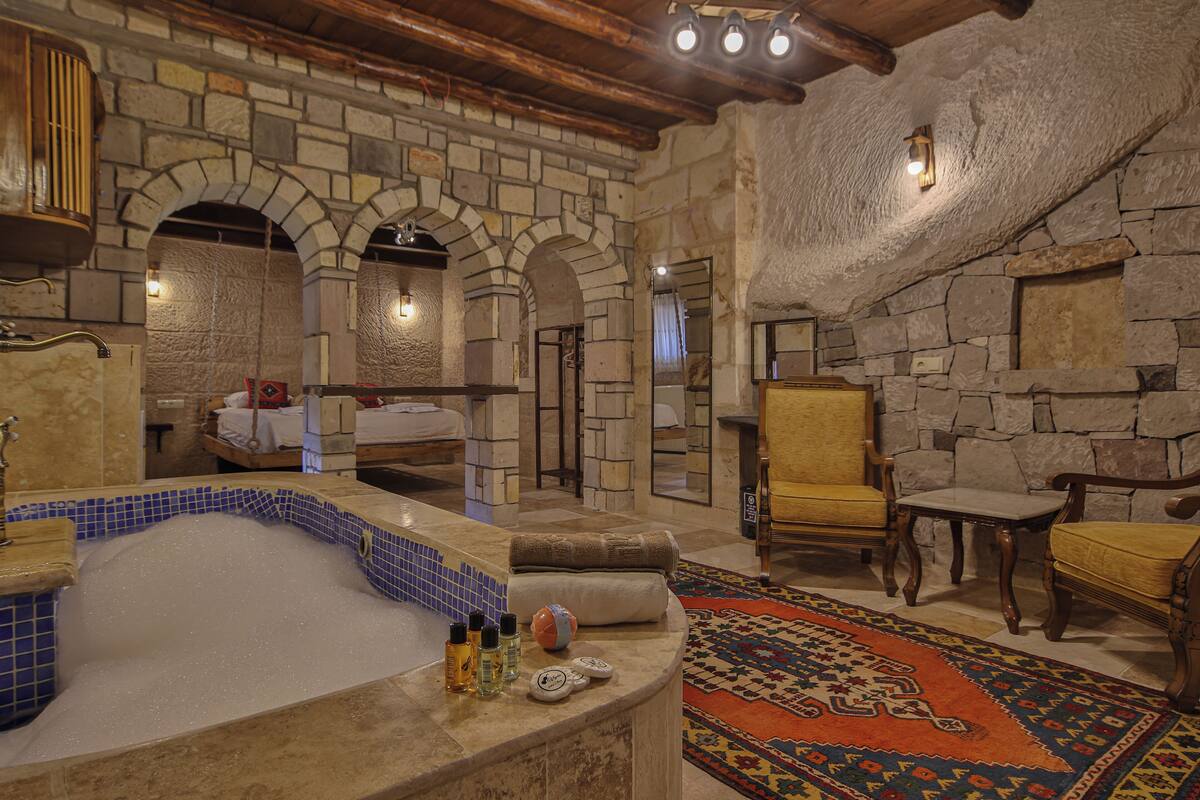 A spa area with a stone wall, a bathtub, and two wooden chairs.