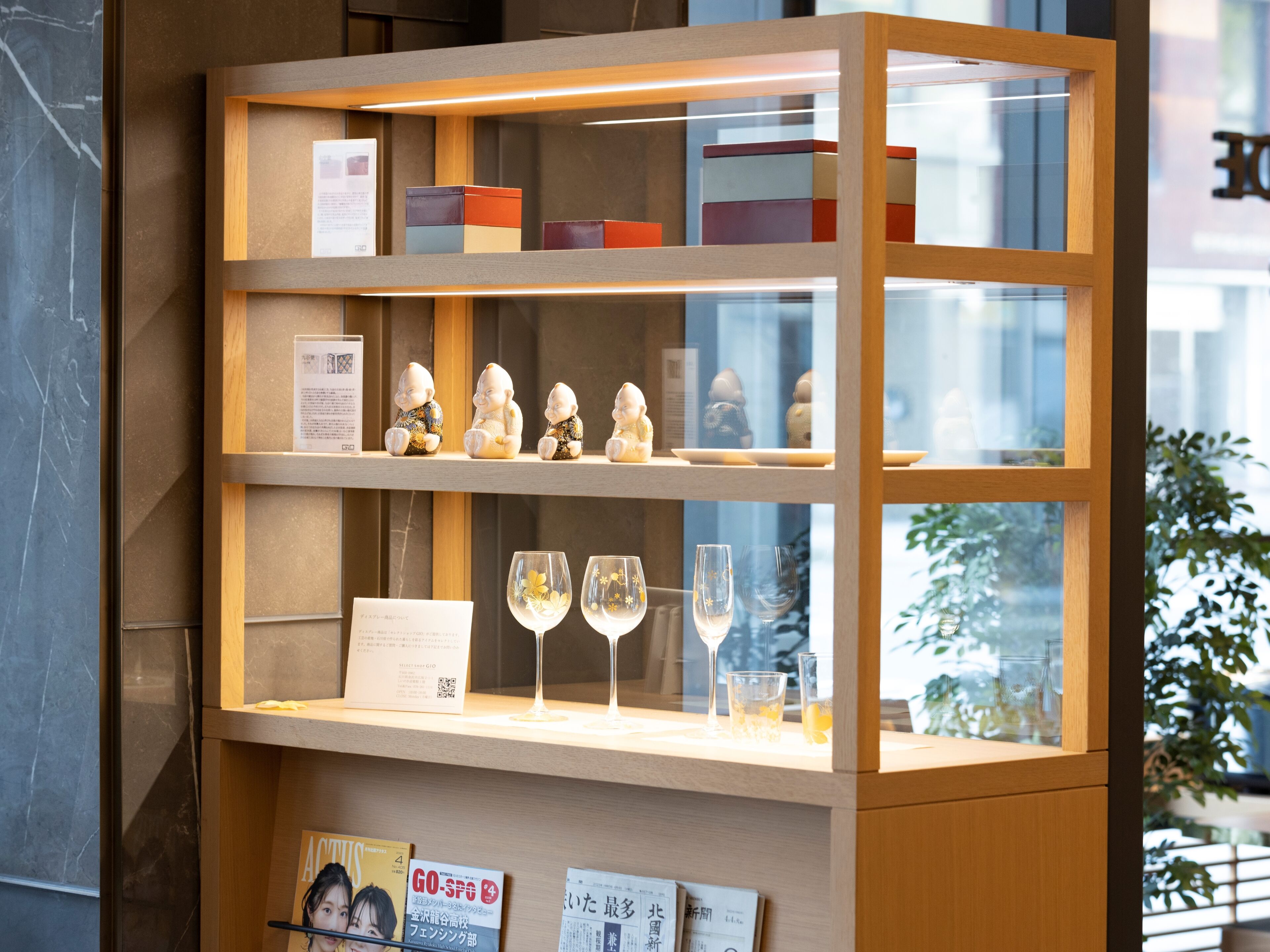 Una vitrina con cristalería, figuritas, un menú y revistas.