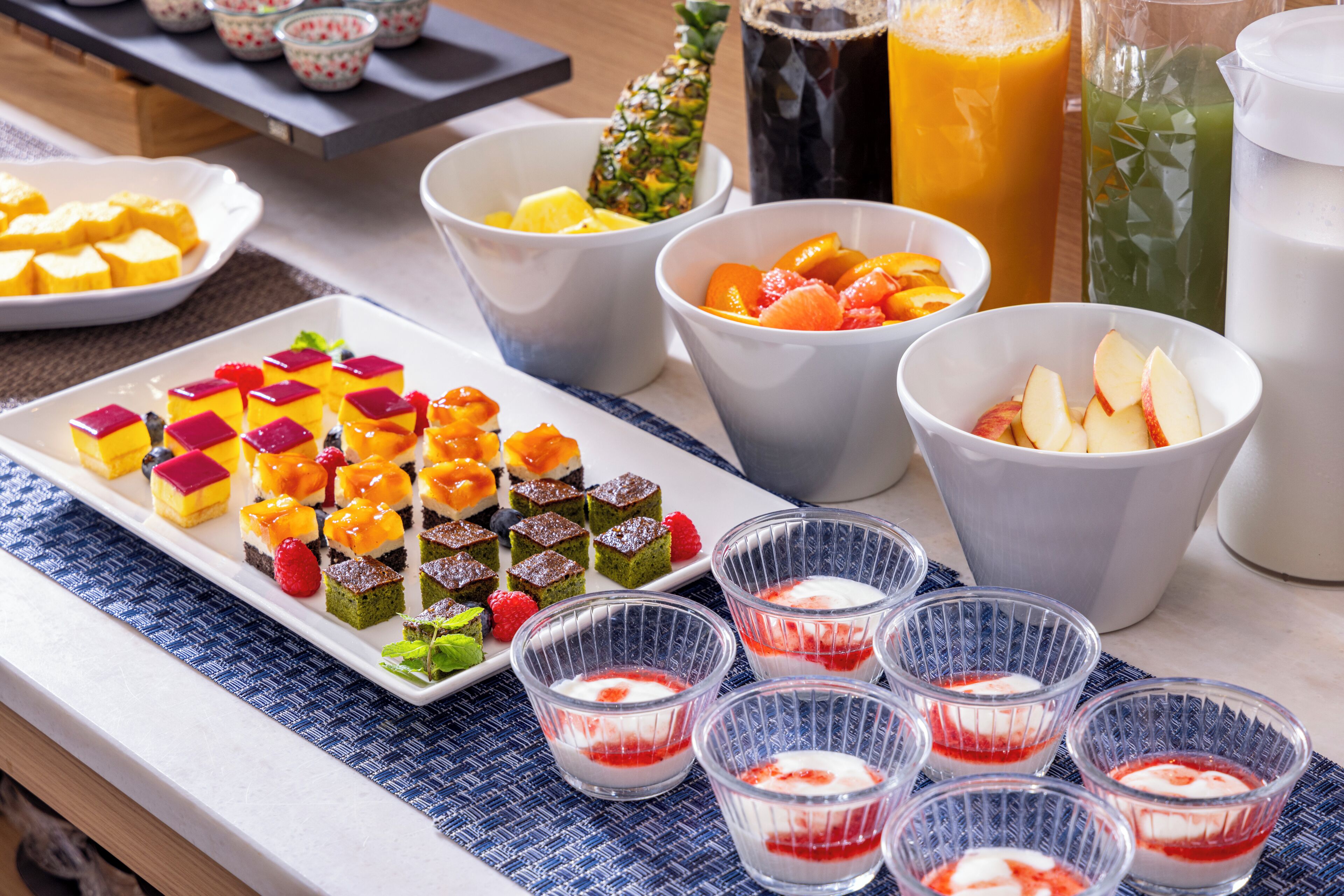 Un bufé con diversos postres, frutas y bebidas.