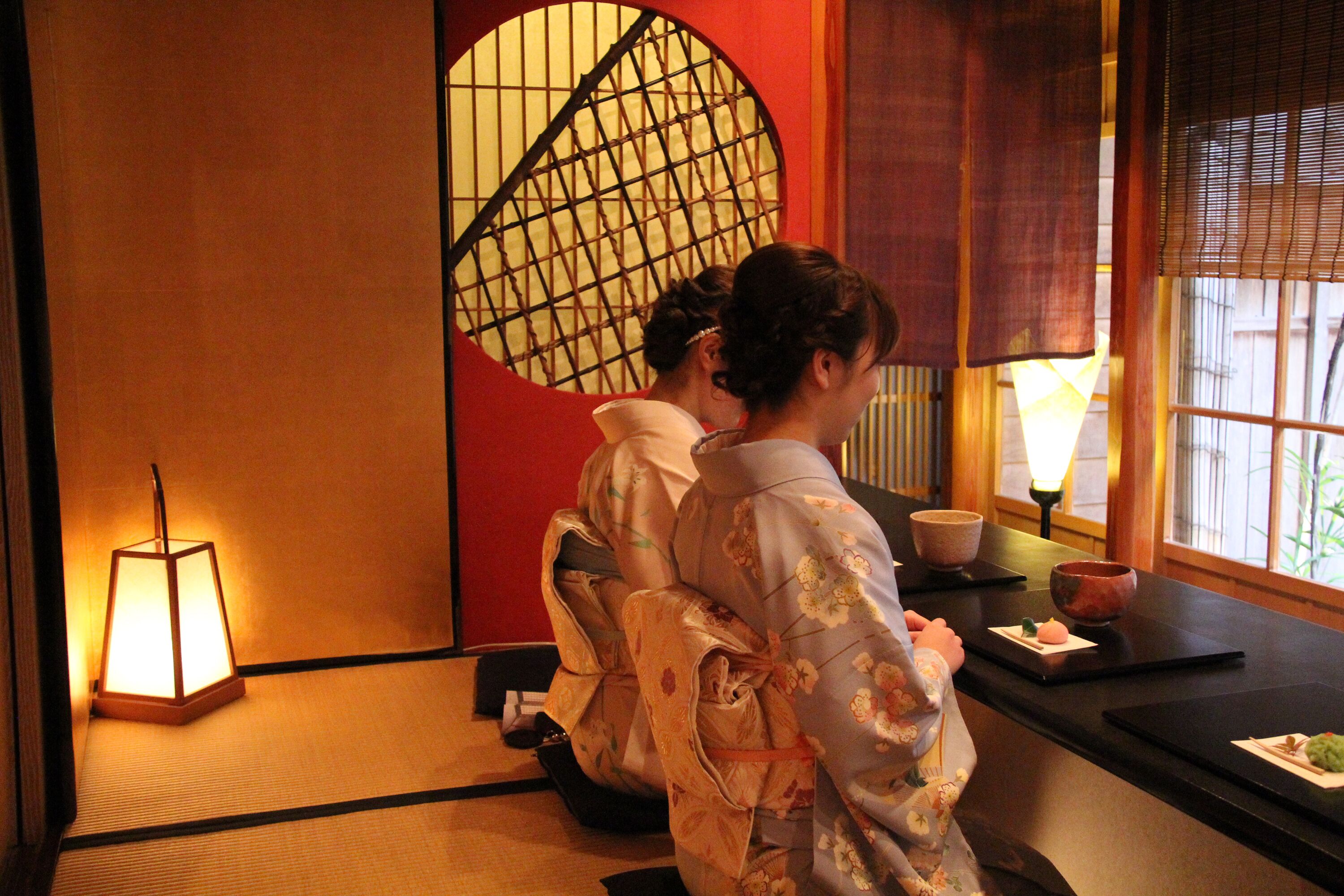 A traditional Japanese room with tatami flooring, a shoji screen, and a low table with a candle and a bowl.
