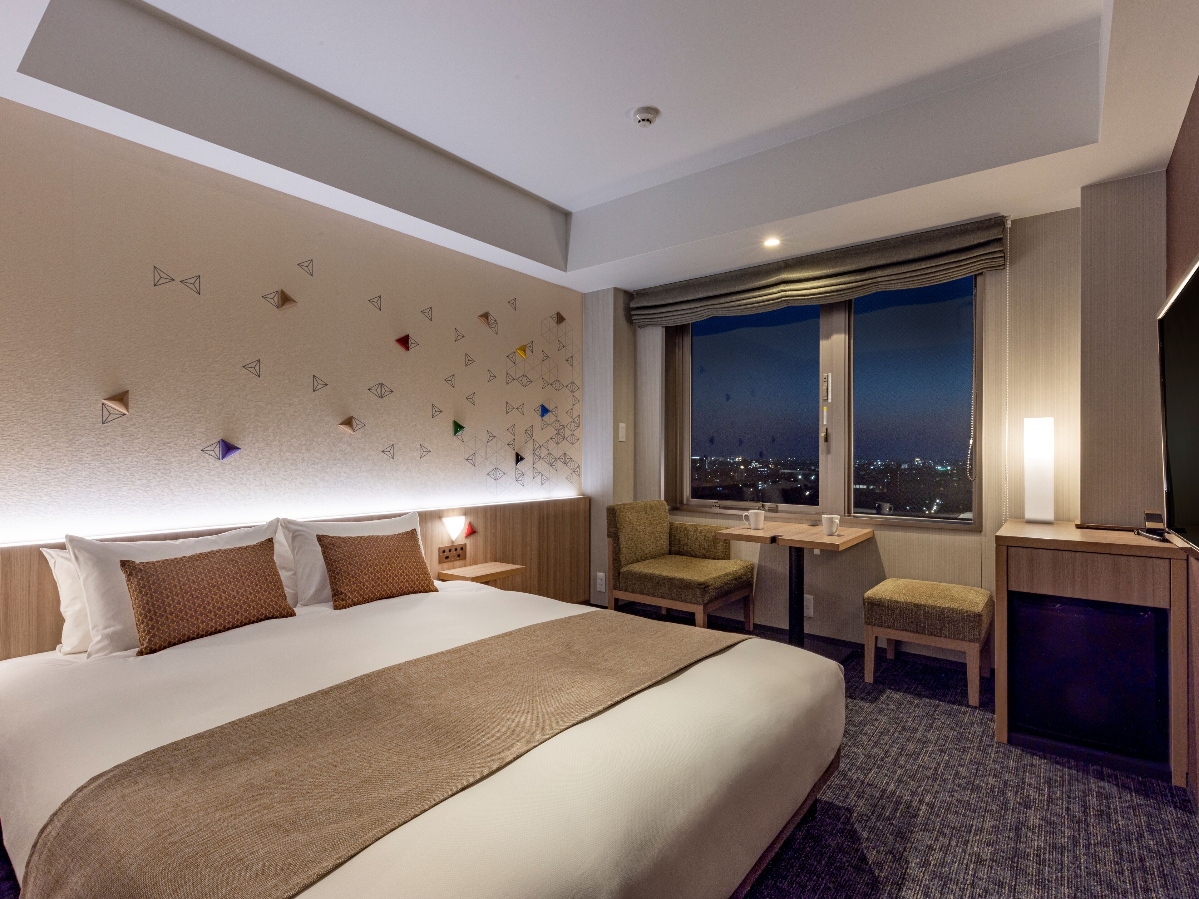 Una habitación de hotel con una cama grande, un escritorio, una silla y un televisor.