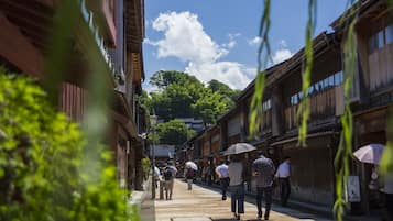 A narrow street with traditional wooden buildings, a clear sky, and people walking.