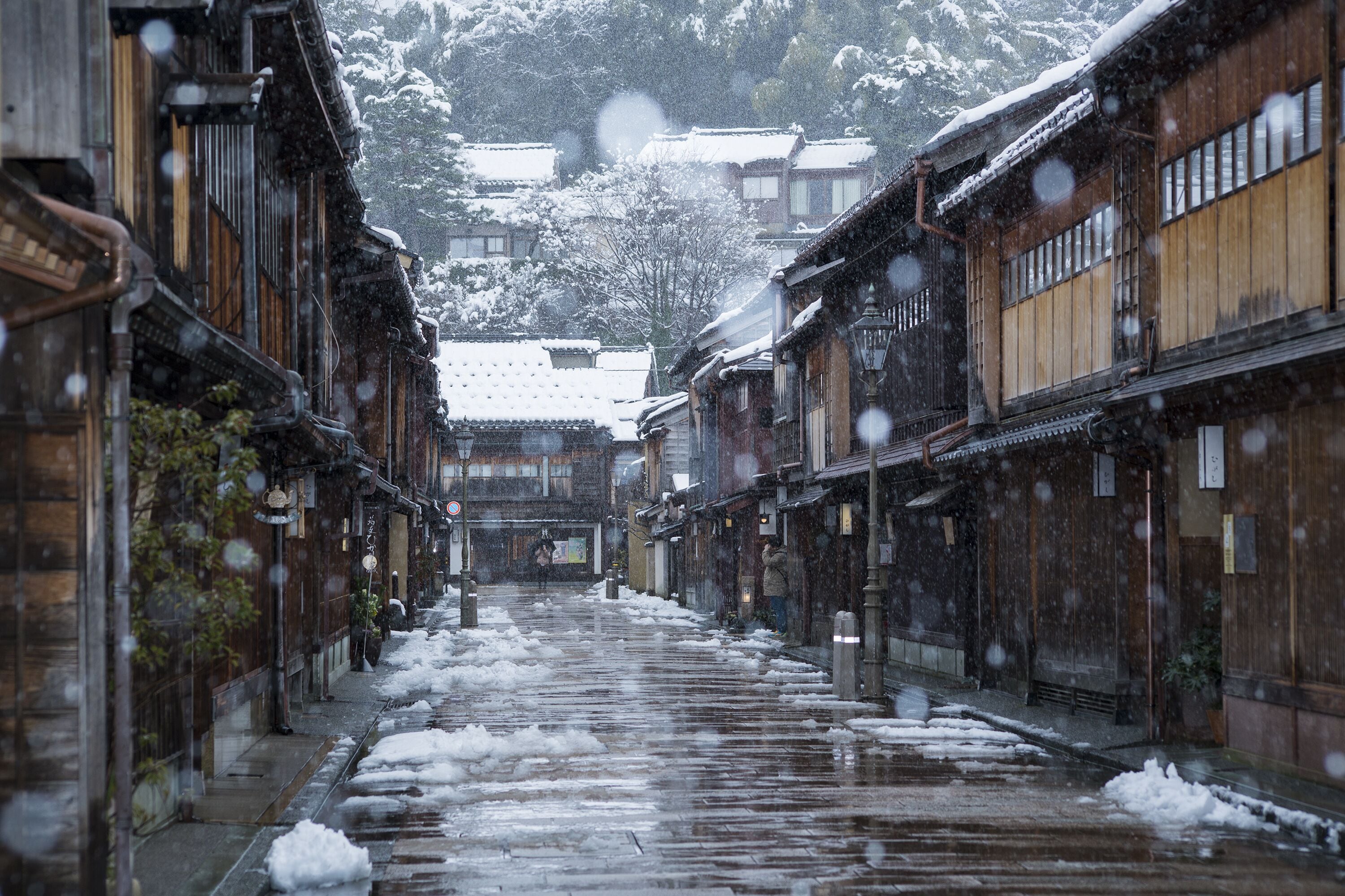 A traditional wooden building with a snow-covered street.