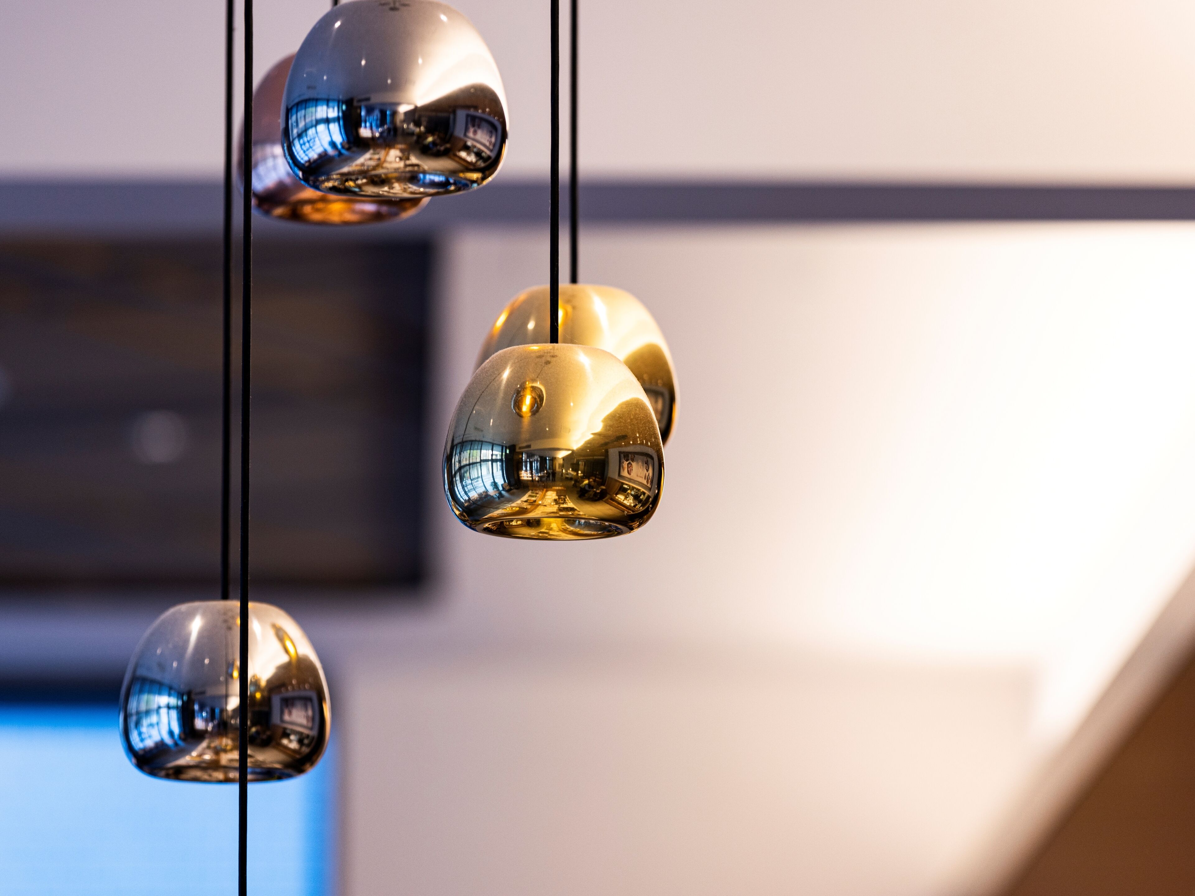 Three hanging spherical light fixtures with a reflective surface.