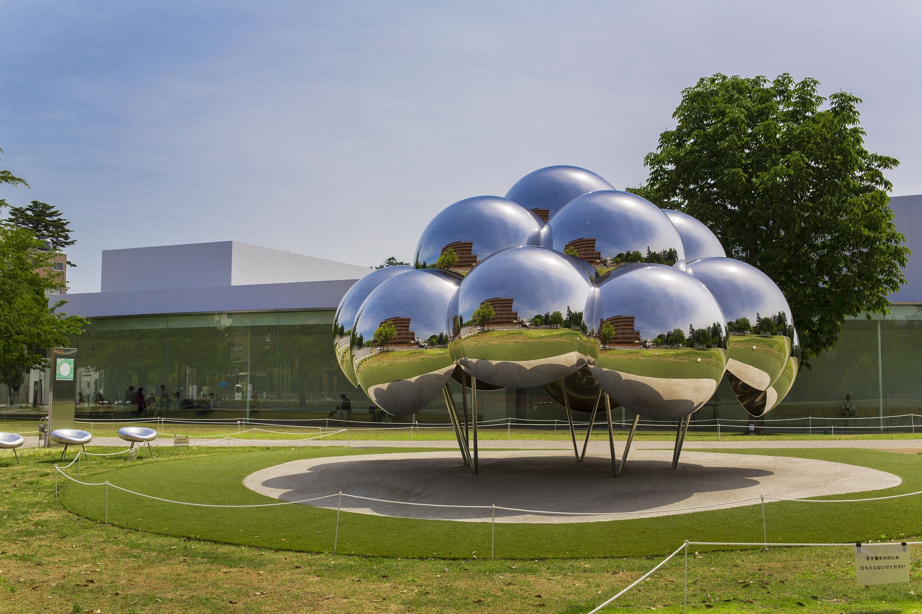 A spherical sculpture installation in an outdoor setting with a modern building in the background.