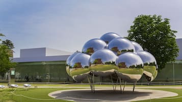 Una instalación escultórica esférica en un entorno exterior, con un edificio moderno al fondo.