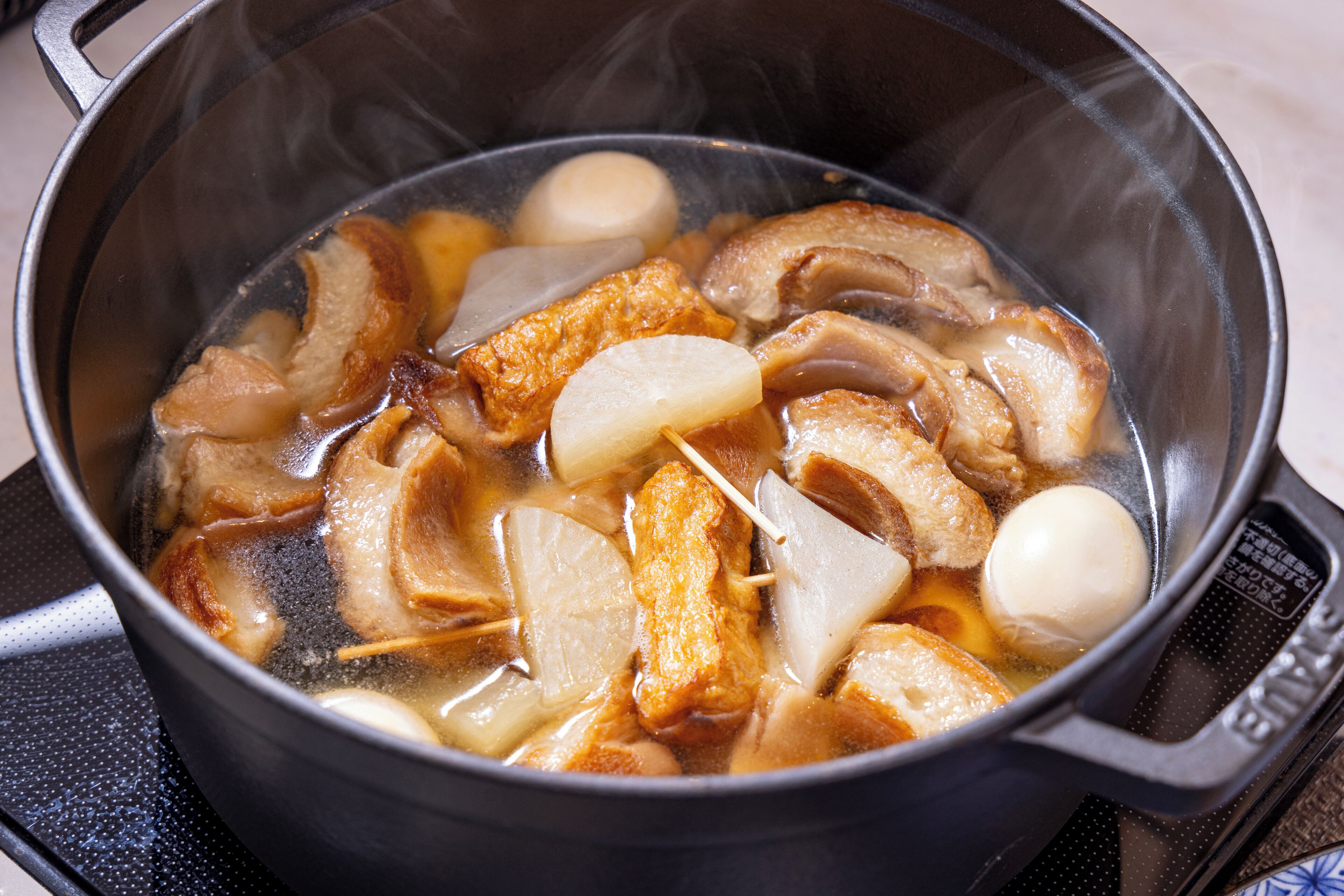Una olla con diversos ingredientes hirviendo en agua, entre ellos carne y verduras.