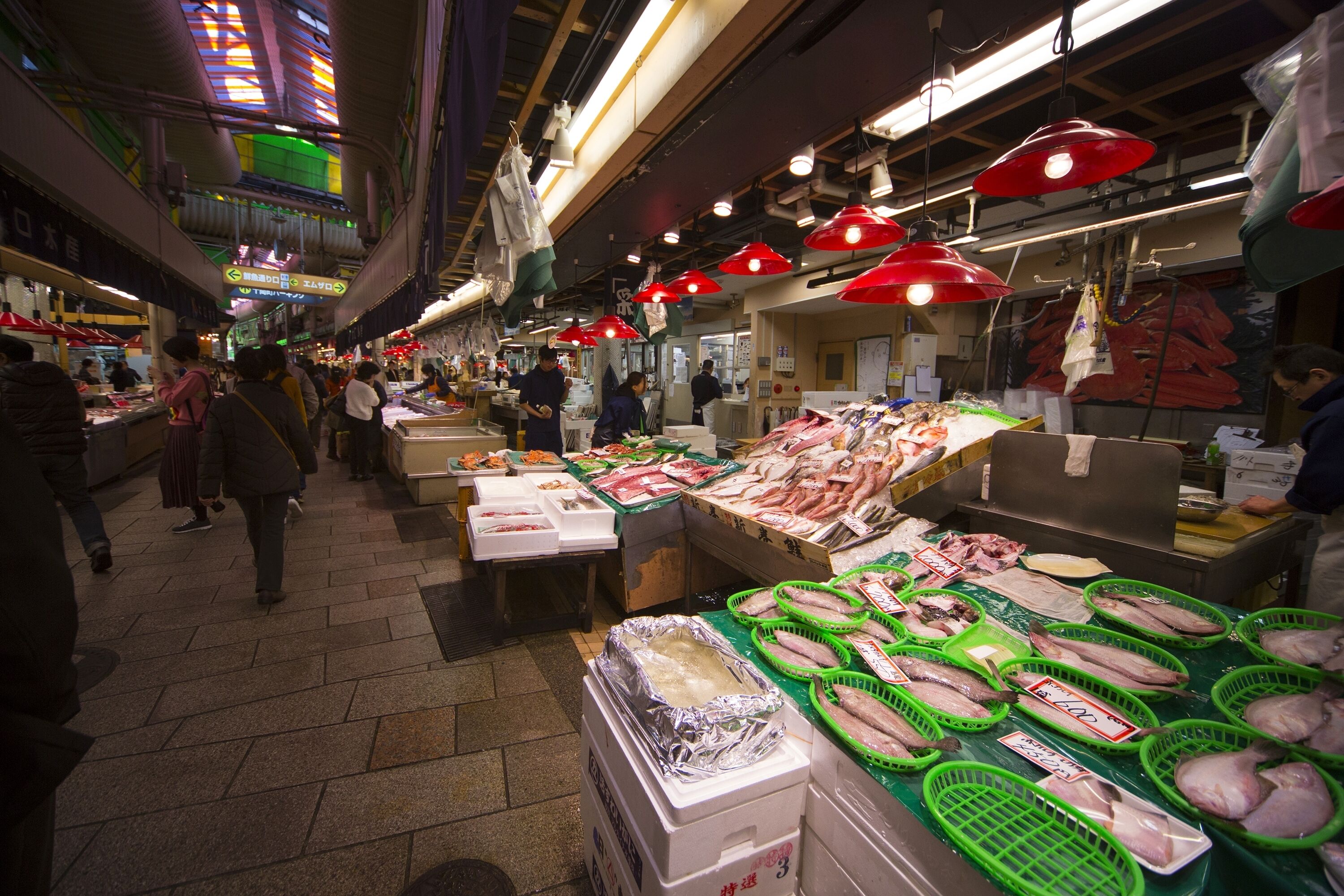 Mercado interno movimentado com diversos quiosques vendendo frutos do mar frescos.
