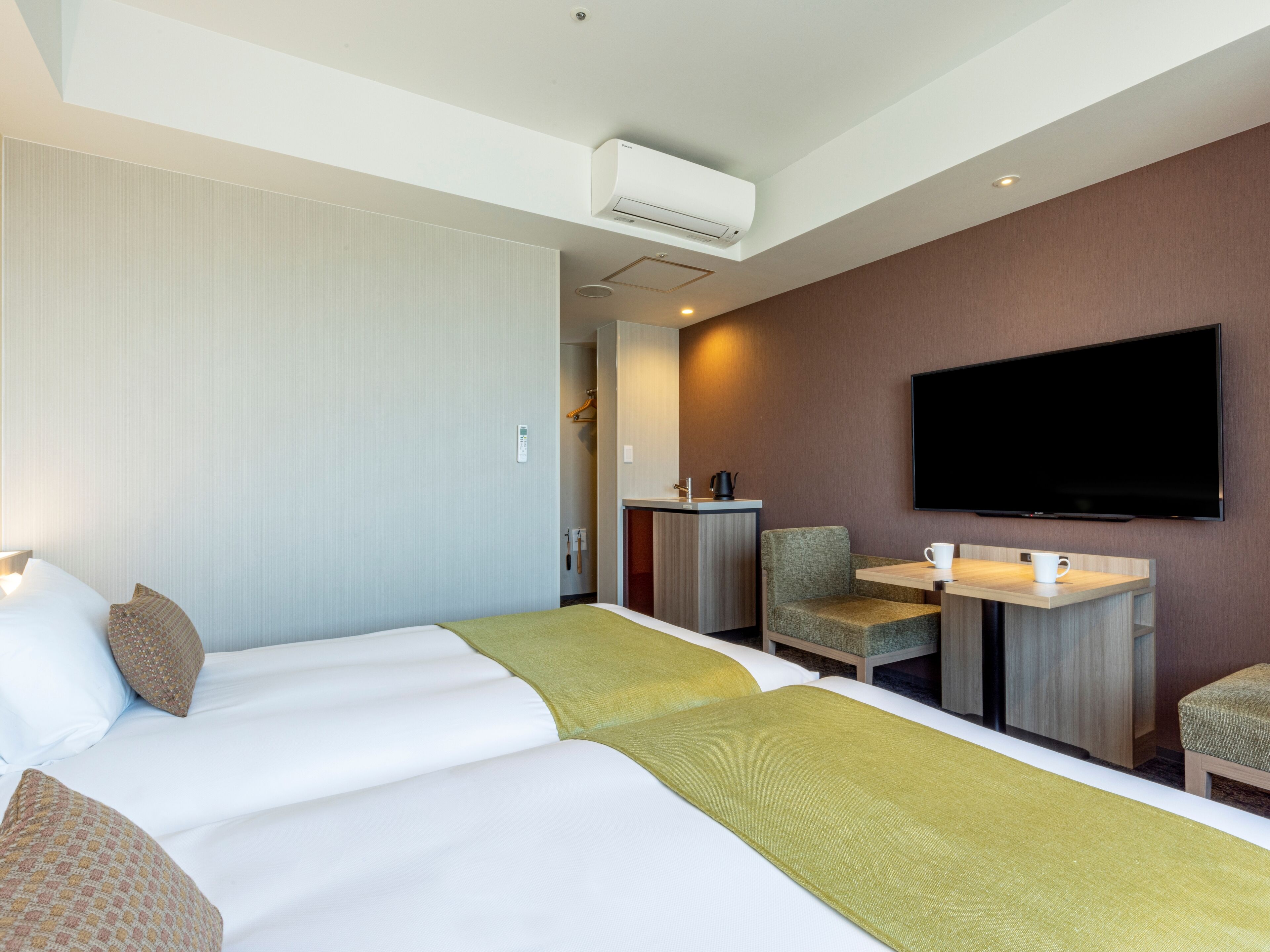 Une chambre d’hôtel comprenant un lit, un bureau avec un téléviseur à écran plat, une chaise et une table basse.