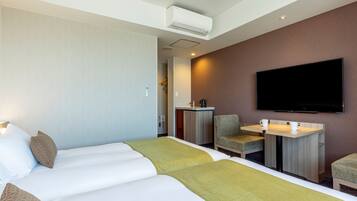A hotel room with a bed, a desk with a flat-screen TV, a chair, and a coffee table.