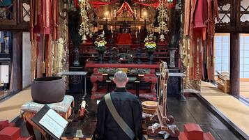A traditional interior with a central altar, red and gold decorations, and a large gong.