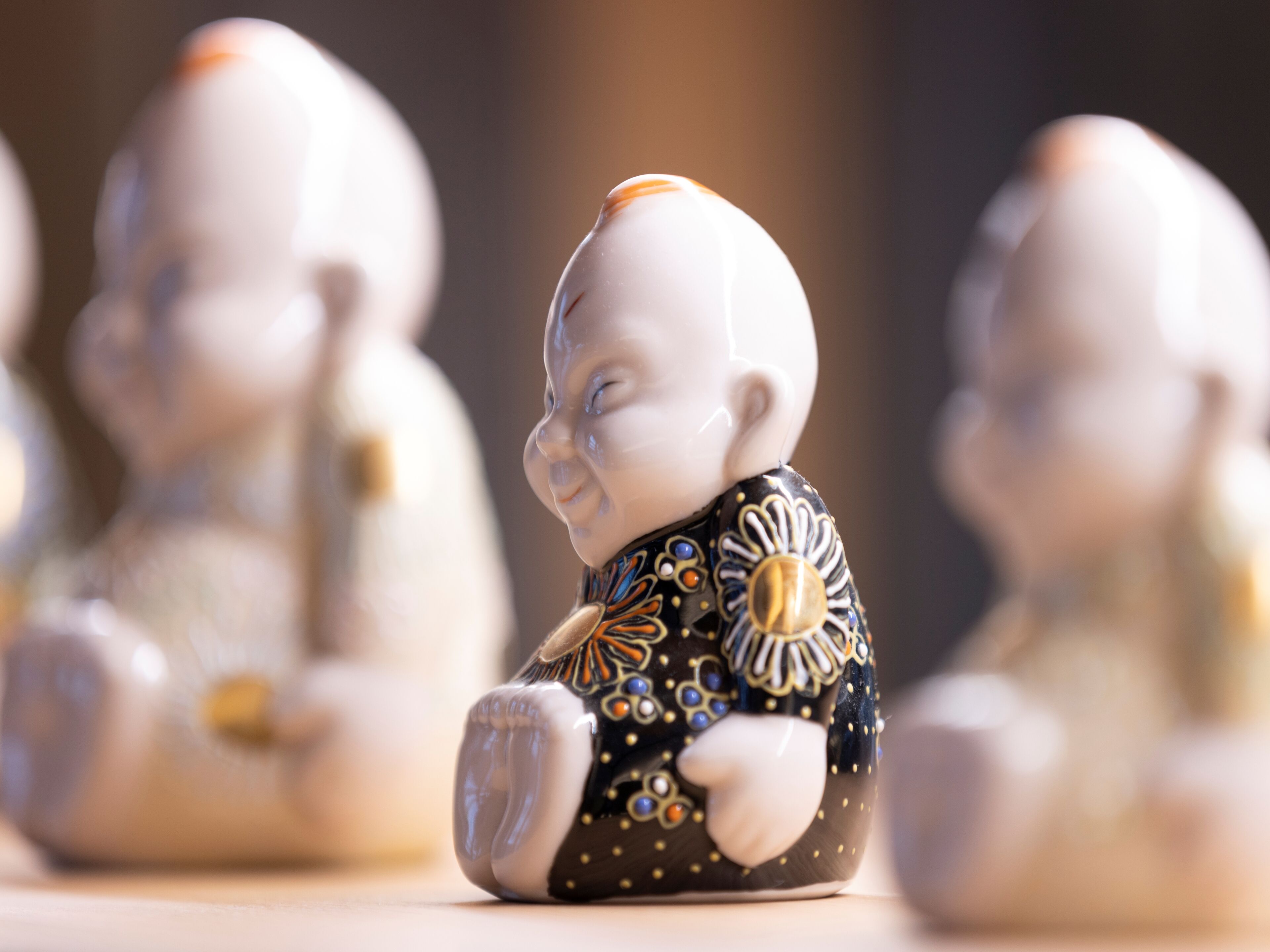 A row of white ceramic figurines with intricate black and gold patterns.