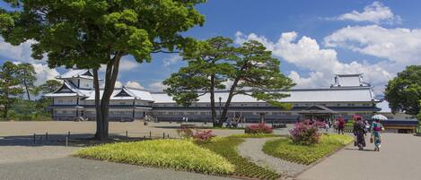 A traditional Japanese building with a tiled roof and a large tree in the foreground.