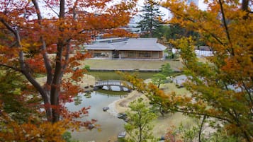 A traditional Japanese building with a pond, a bridge, and autumn foliage.