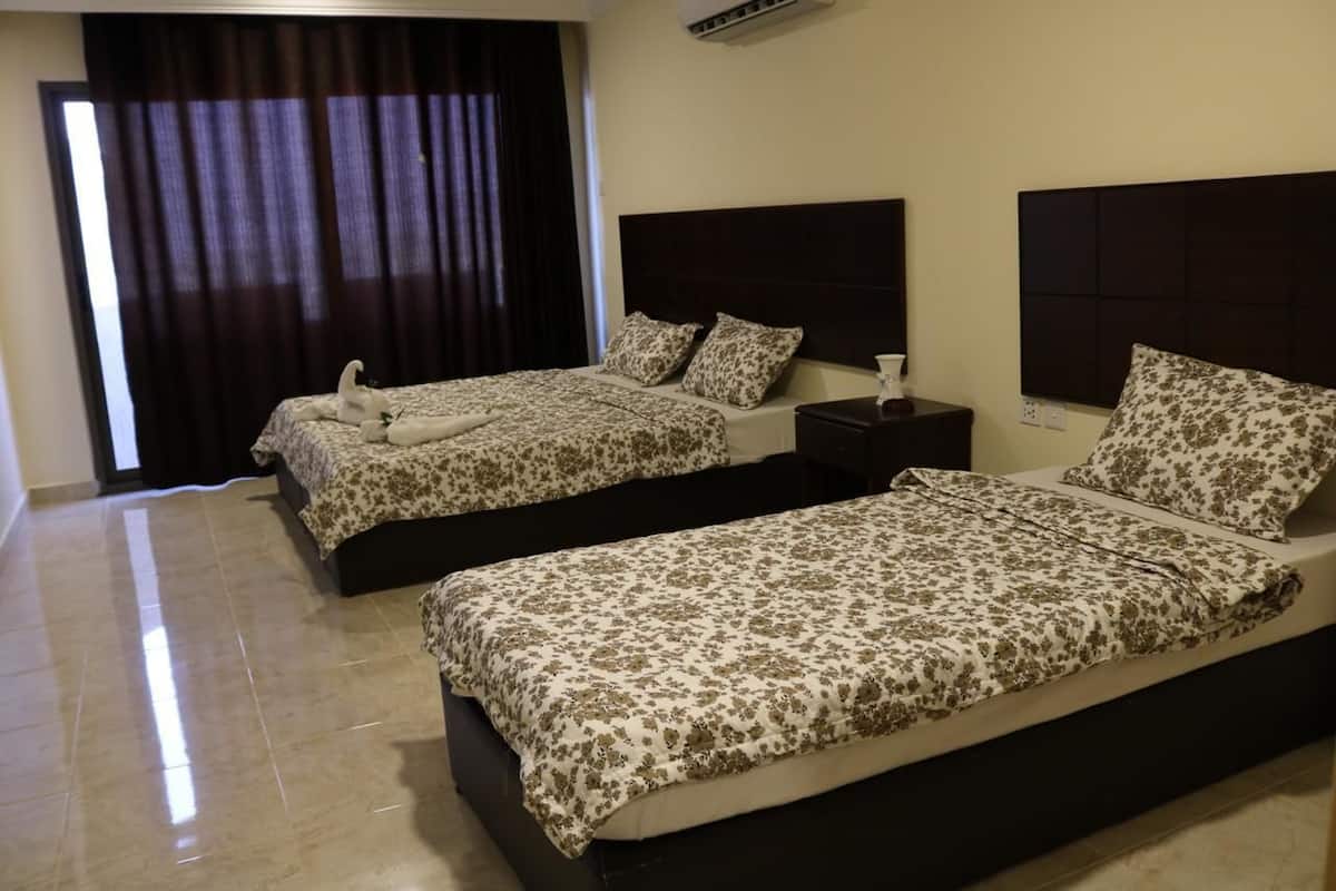 A hotel room with two beds, dark headboards, and a large window with curtains.