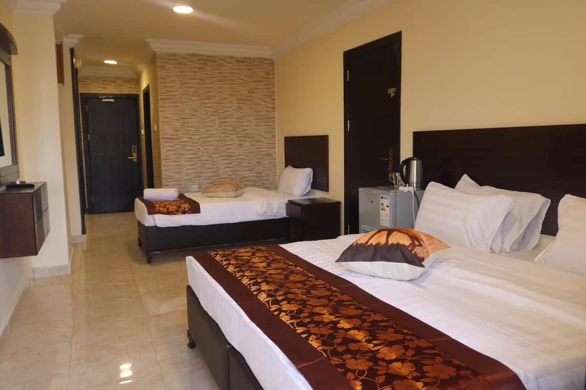 A hotel room with two beds, a large mirror, a stone wall, and a dark wooden headboard.