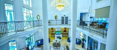 A multi-level hotel lobby with a grand chandelier, high ceilings, and a central seating area.