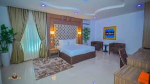 A modern hotel room with a large bed, a desk, and a seating area. - JJ Mas Hotel (Owerri)