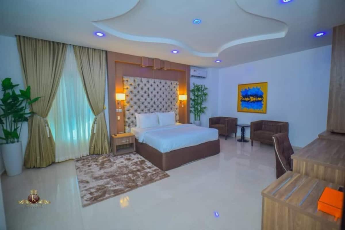 A modern hotel room with a large bed, a desk, and a seating area.