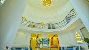 A hotel lobby with a grand chandelier, a reception desk, and a sign indicating hotel and suites. - JJ Mas Hotel (Owerri)