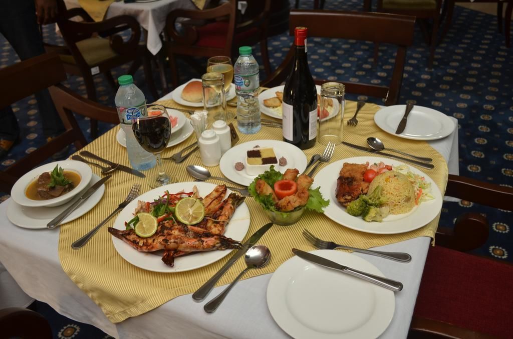 A dining table set with plates of food, cutlery, and beverages.
