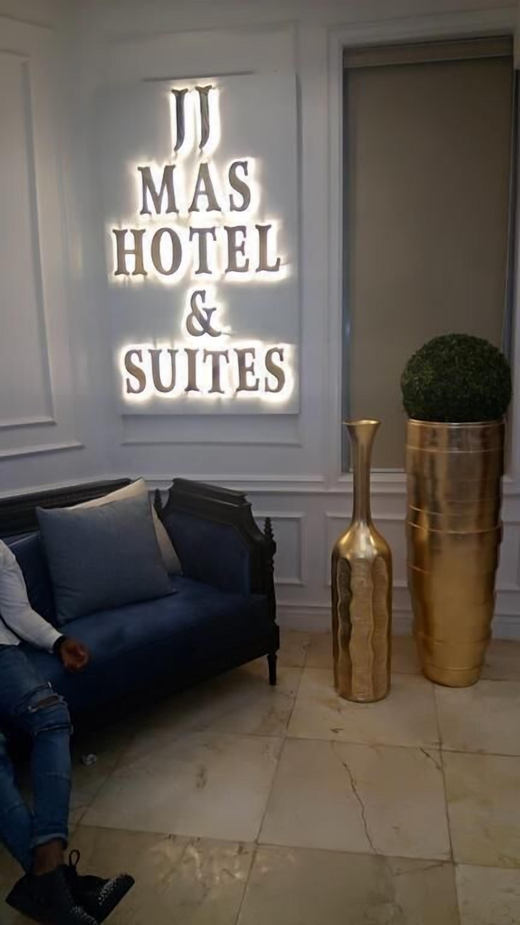 A hotel sign with the text "MAS HOTEL & SUITES" and a blue sofa with cushions.
