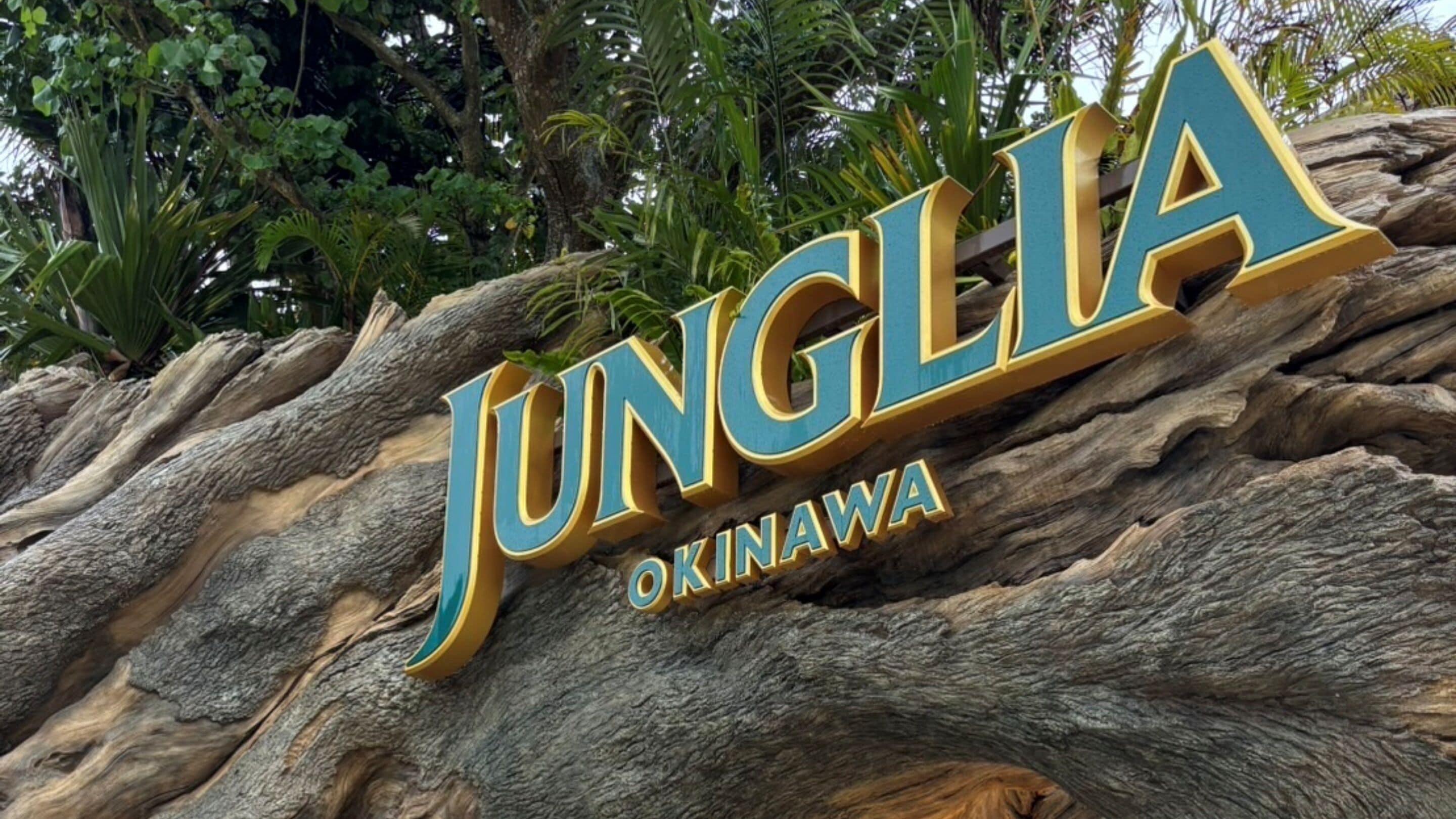 Un letrero grande y llamativo con el nombre 'JUNGIA OKINAWA' sobre una superficie rocosa con textura.