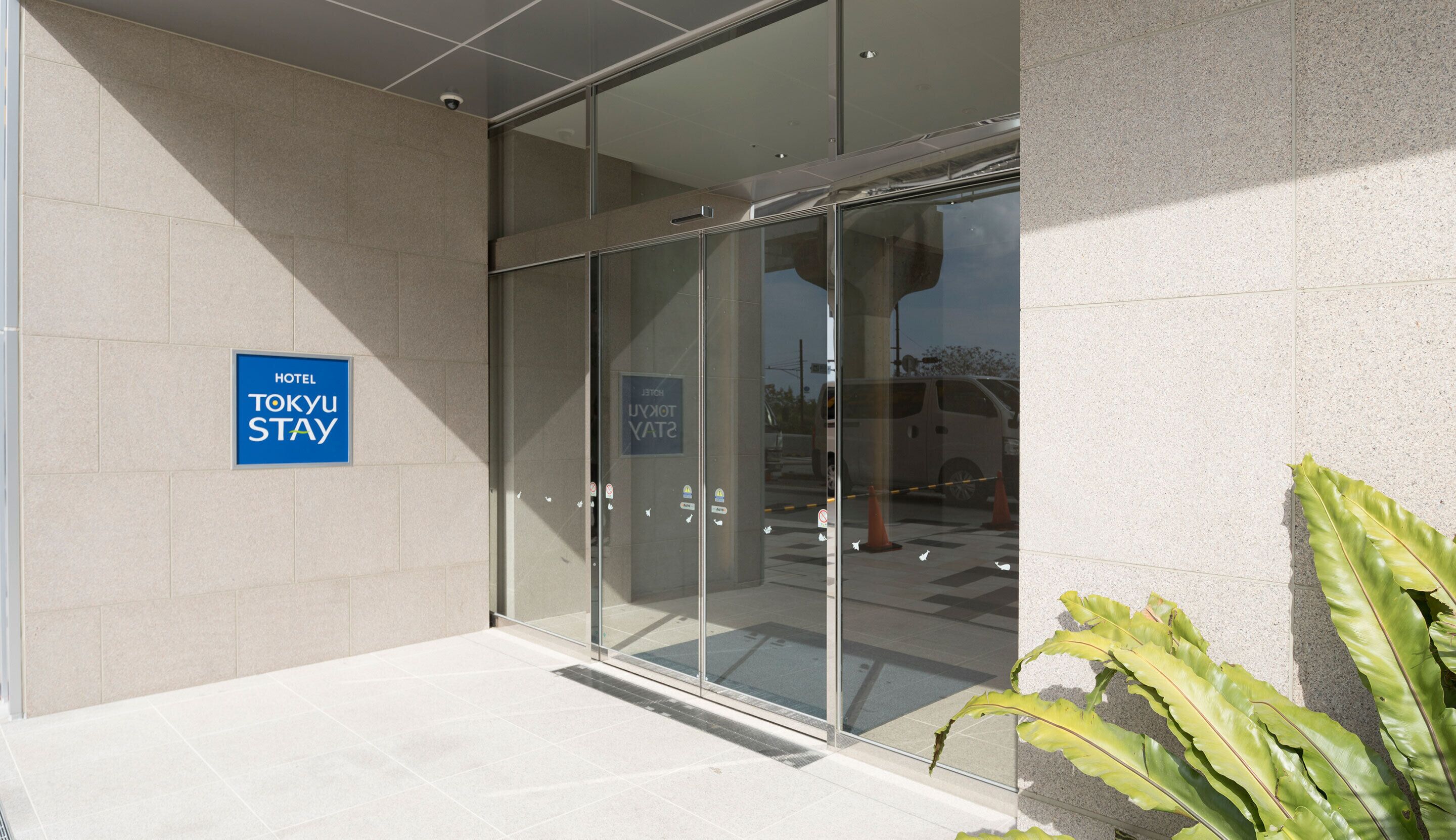 Entrada de un hotel con un cartel que dice 'HOTEL TOKYU STAY'.