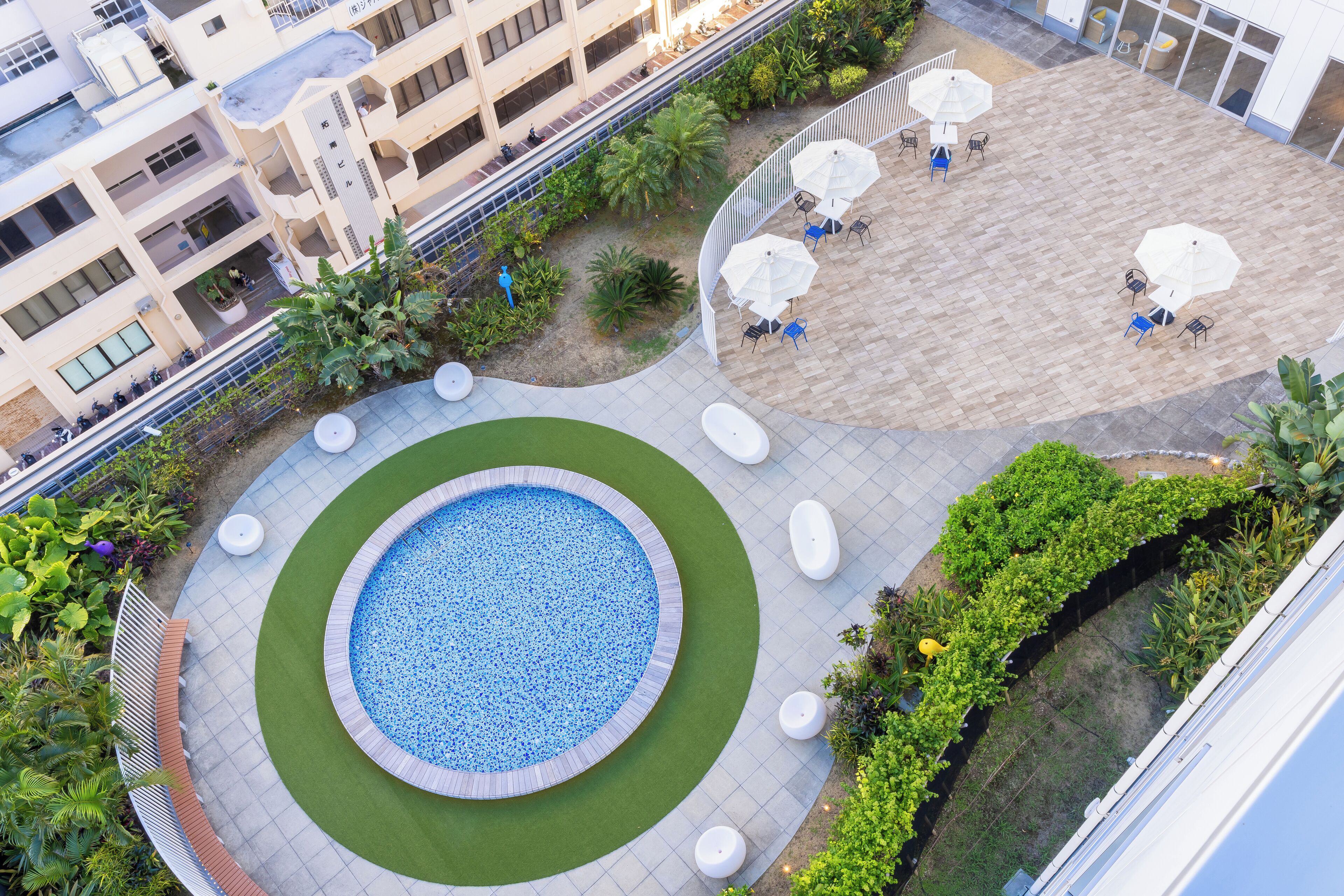 A rooftop pool area with a circular pool, surrounding seating, and a landscaped garden.