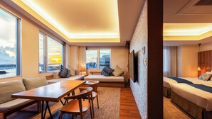 A modern hotel room with a large window, a sofa, a dining table, and a bed. - Tokyu Stay Okinawa Naha (Naha)