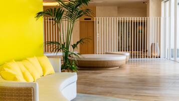 A modern interior with a curved white sofa, a round seating area, and a large potted plant.