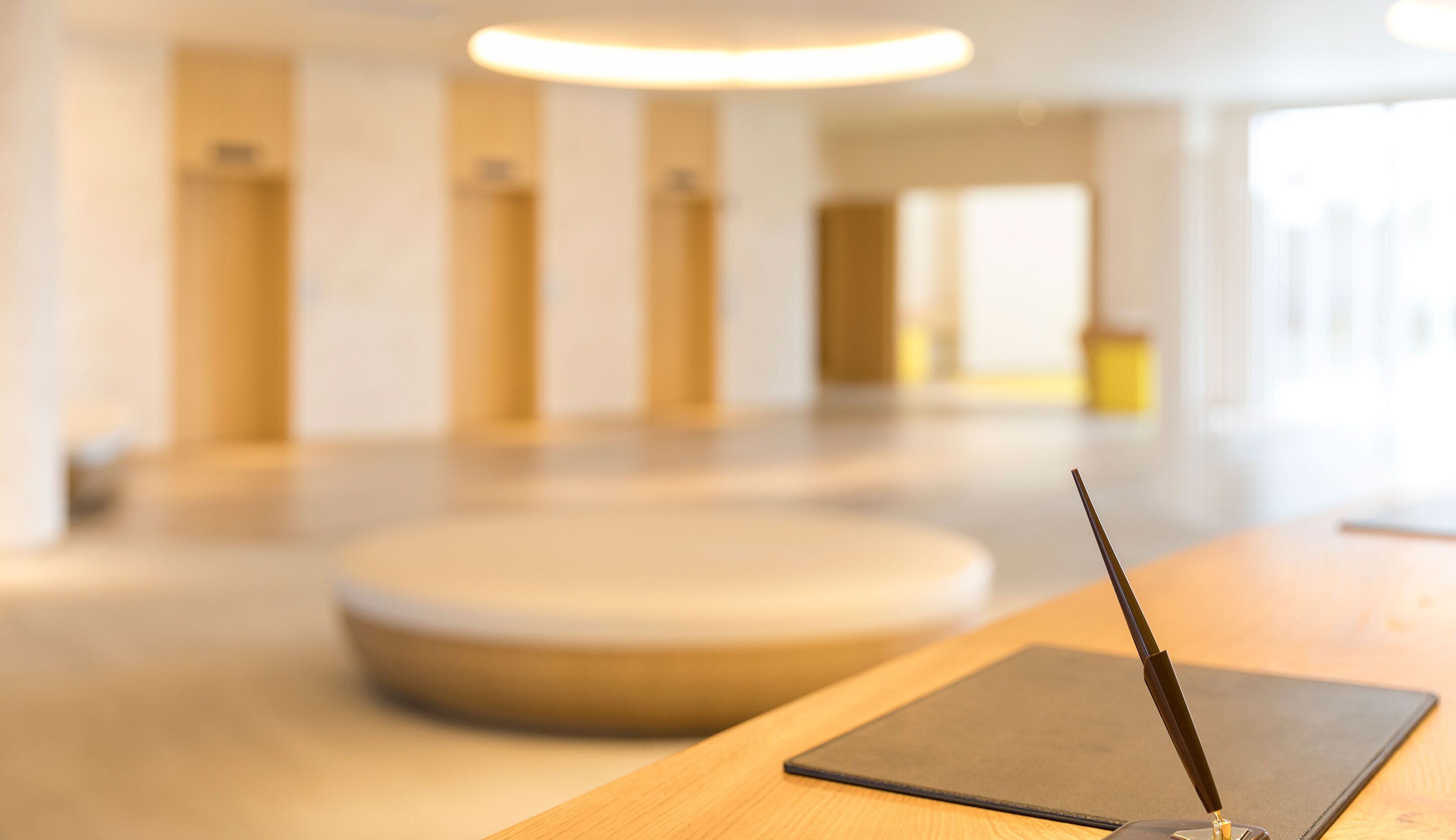 Une pièce moderne et bien éclairée, avec une table en bois, une tablette noire et un stylo noir.