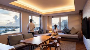 Une chambre d’hôtel moderne dotée d’une grande fenêtre, d’un canapé, d’une table à manger et d’un téléviseur.