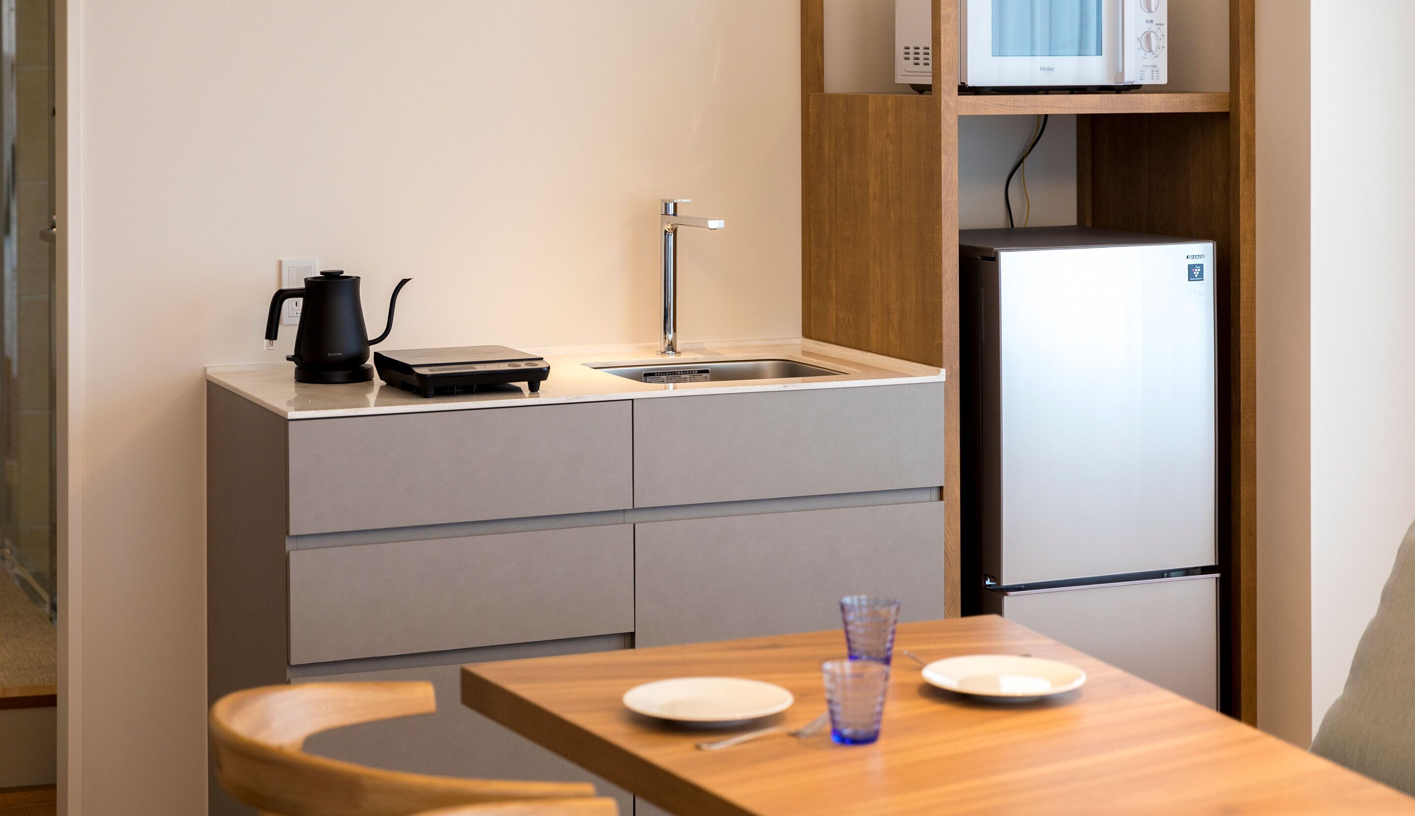 A compact kitchenette with a sink, a kettle, a microwave, and a refrigerator.