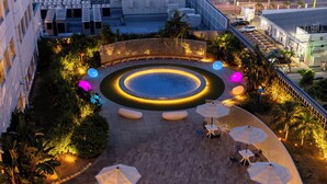 An outdoor courtyard with a circular water feature, seating areas, and umbrellas. - Tokyu Stay Okinawa Naha (Naha)