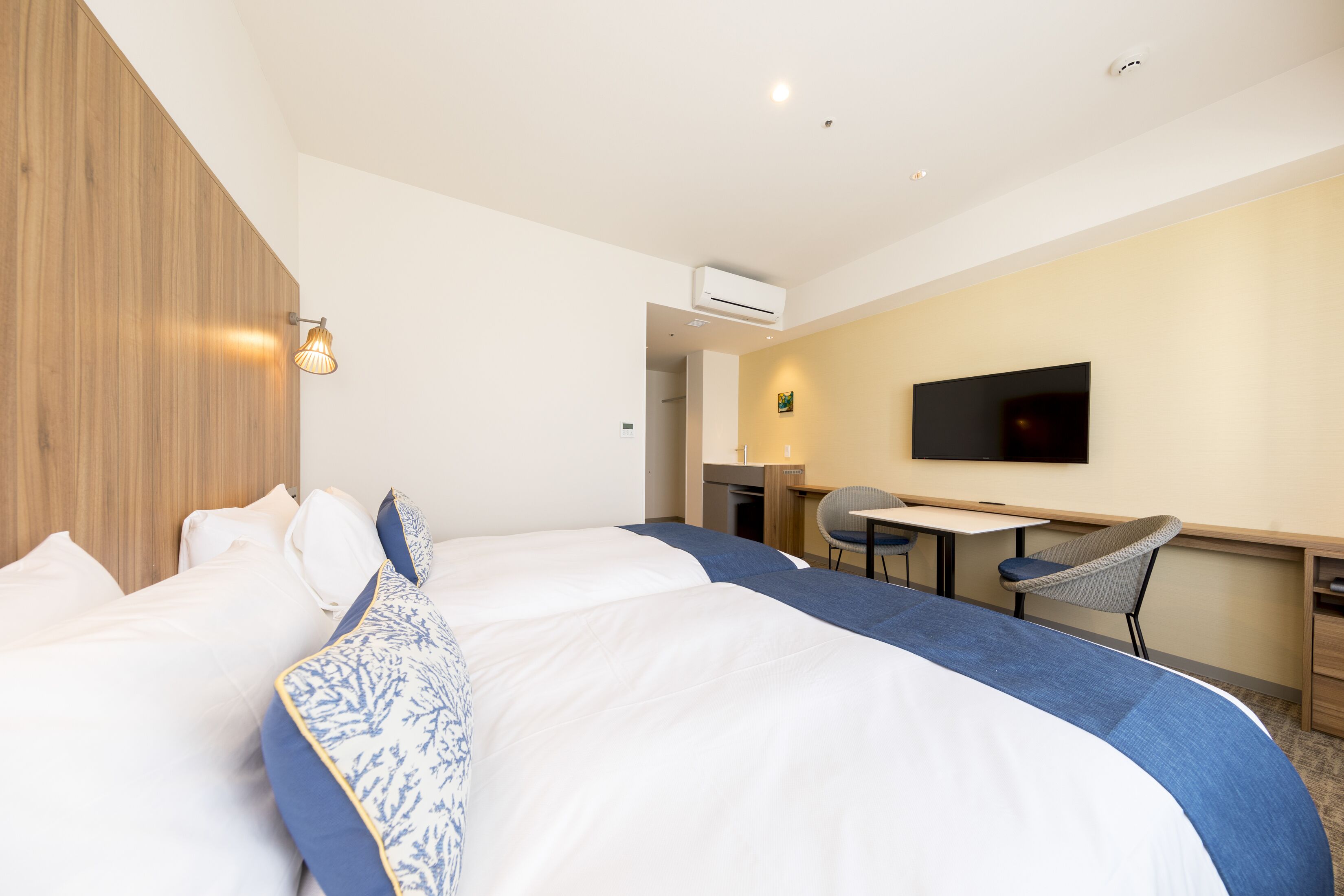 Habitación de hotel con una cama grande, un escritorio, una silla y un televisor en la pared.