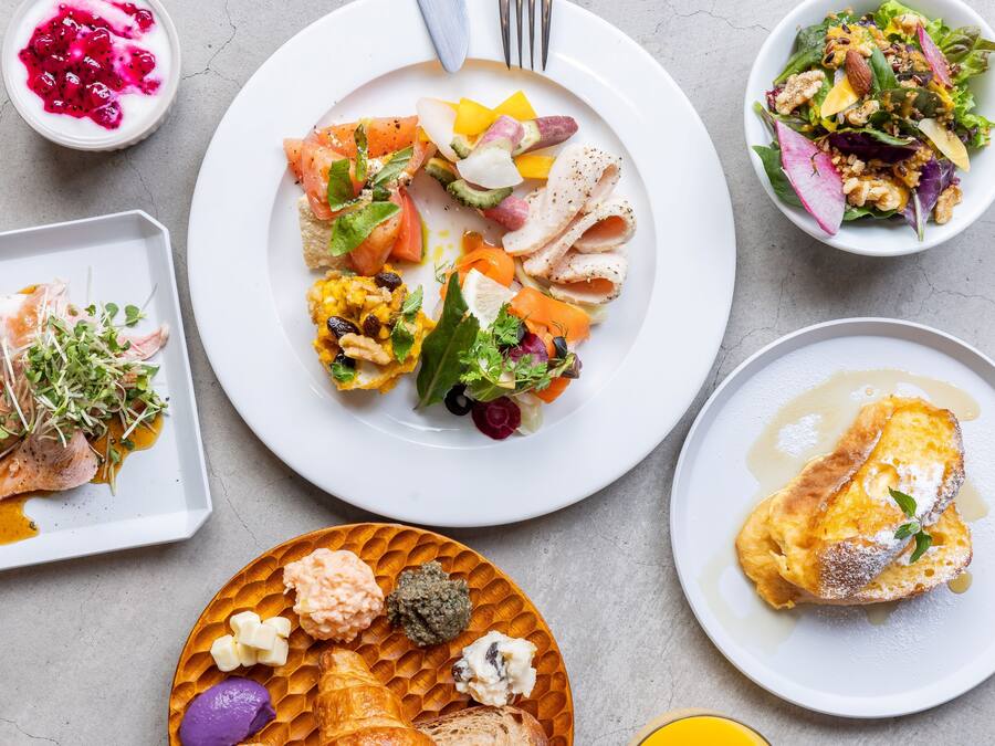 Verschiedene Gerichte, darunter ein Salat, ein Croissant und eine Nachspeise, auf einem Tisch.