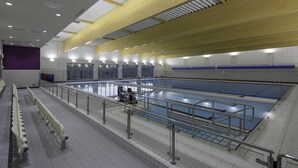 An indoor swimming pool with a wooden ceiling, tiled walls, and a seating area with benches. - Scarman - Warwick Conferences (Coventry)