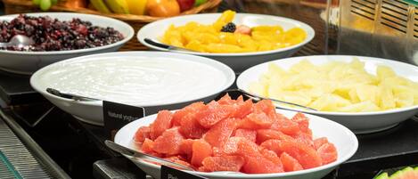 Un bufé con diversas opciones de fruta, como sandía, piña y uvas.