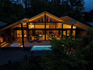 Une maison moderne dotée d’une grande façade vitrée, d’une piscine et d’un espace patio.