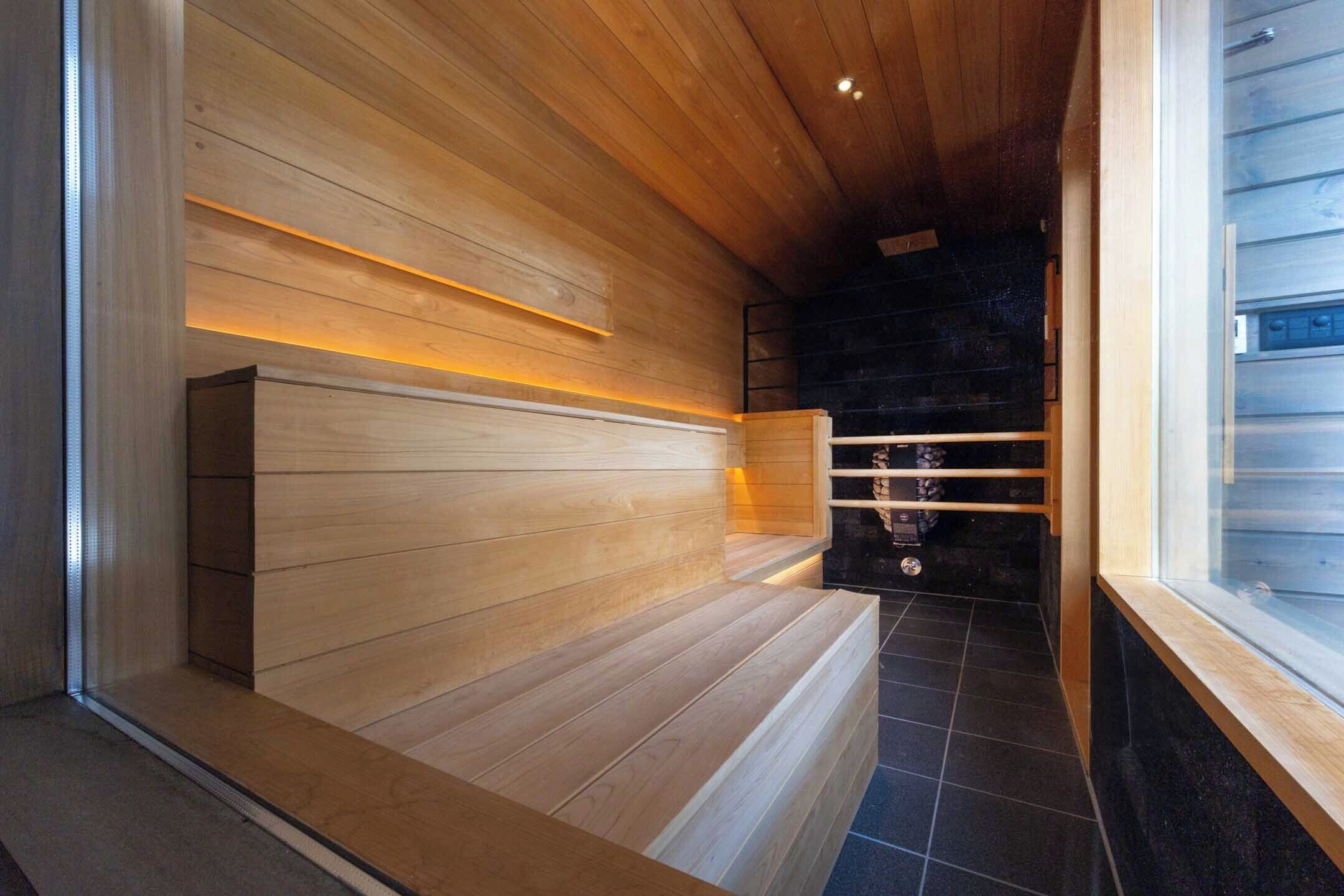 Un interior moderno con paneles de madera, un banco y un piso cubierto de baldosas negras.