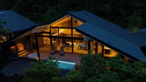 A modern house with a large open-plan living area, a swimming pool, and a covered outdoor seating area.